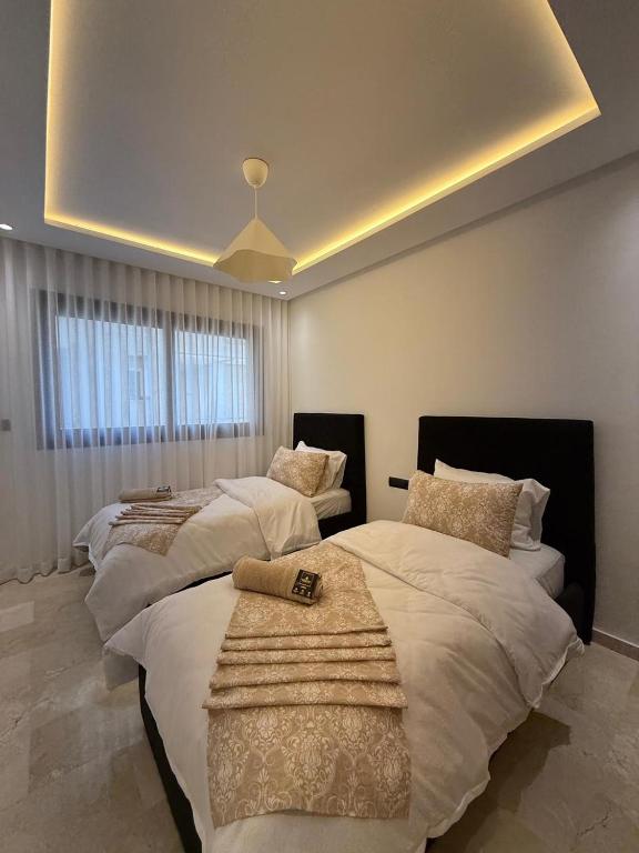 a bedroom with two beds and a large window at Appartement modern a malabata hills in Tangier