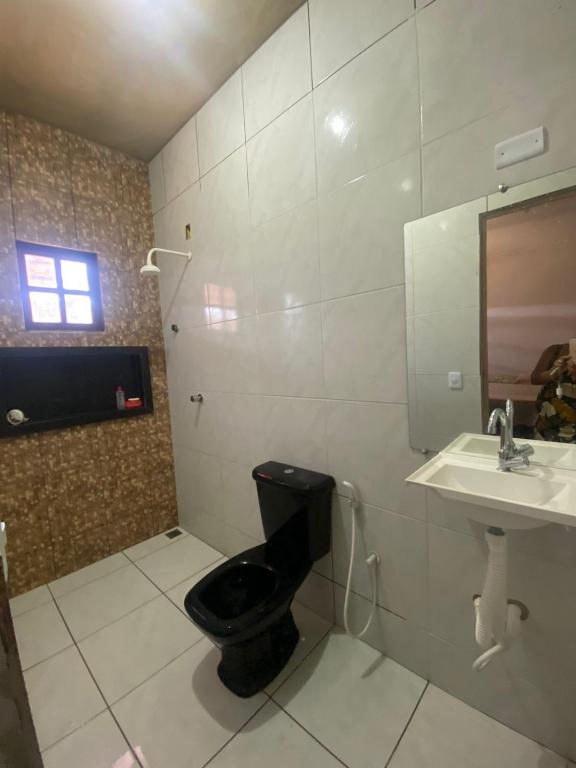een badkamer met een zwart toilet en een wastafel bij Casa imperr in Aracati