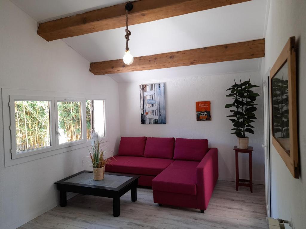 a living room with a red couch and a table at Maison avec jacuzzi et jardin privé, proche plage in Le Pradet
