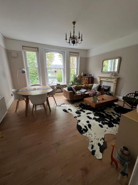 - un salon avec une table et un tapis de vache dans l'établissement Large garden-view room, 20 min from Central London, in a stylish period property in Lee, with free parking and a friendly Jack Russell, à Londres