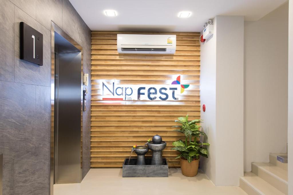 A small elevator landing with the hotel logo, decorative statues and stairs leading upward.