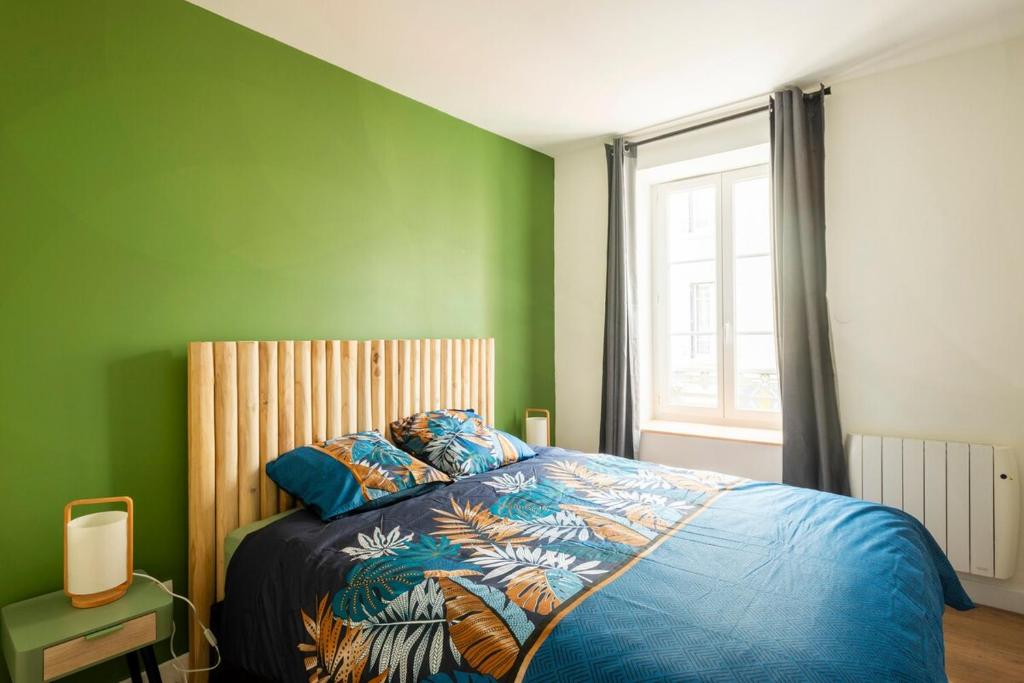 a bedroom with a bed with a blue comforter and a window at Le Goupil in Chalon-sur-Saône