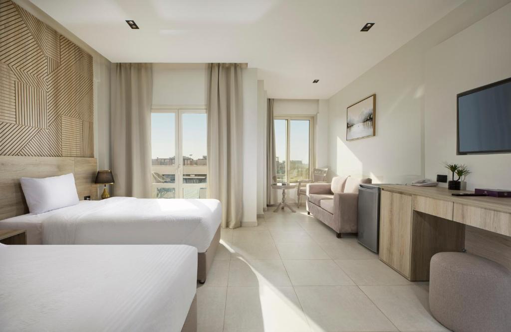 a hotel room with two beds and a television at Rivana Residence New Cairo - Pool & GYM Access in Cairo
