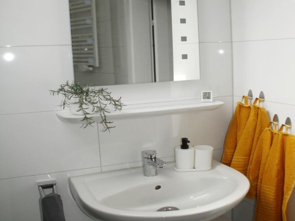 a bathroom with a sink and a mirror and yellow towels at Cozy Apartment in Bedburg-Hau in Bedburg Hau