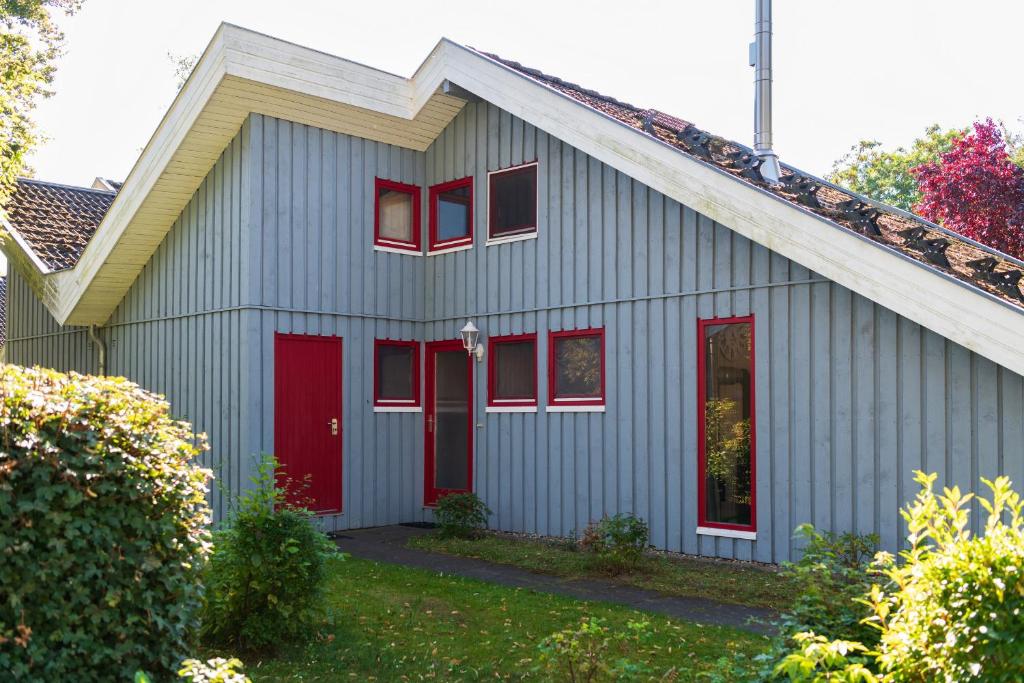una casa gris con puertas rojas y ventanas rojas en Wildgans 48, en Mirow