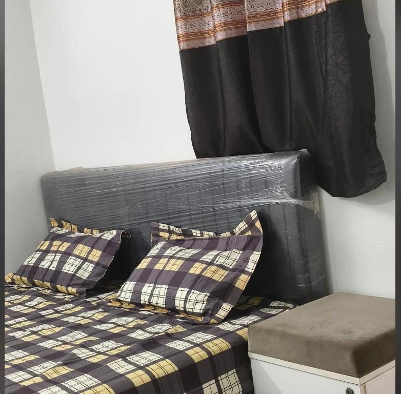 a bed with plaid pillows and a window at dholavira dwarkadhish home stay in Dholovira