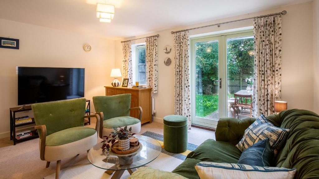 ein Wohnzimmer mit Sofa, Sesseln und Fernseher in der Unterkunft Wildflowers Cottage in Bourton on the Water