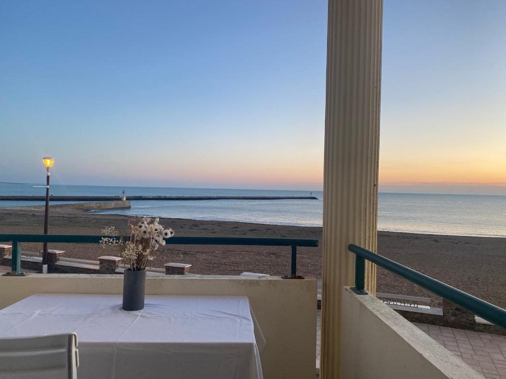 einen Tisch mit einer Vase Blumen am Strand in der Unterkunft Au Bord De L'océan Vue Mer in Saint-Gilles-Croix-de-Vie