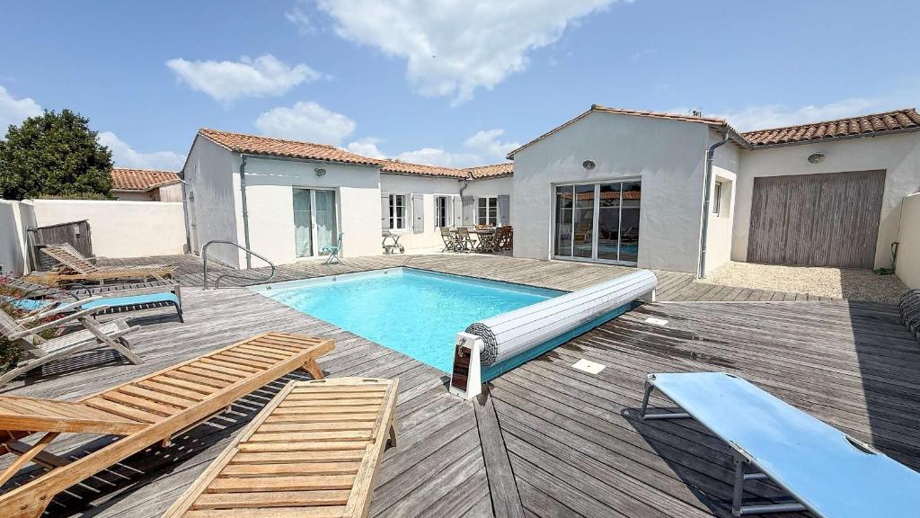 a backyard with a swimming pool and a wooden deck at Belle maison familiale avec piscine et parking in Loix