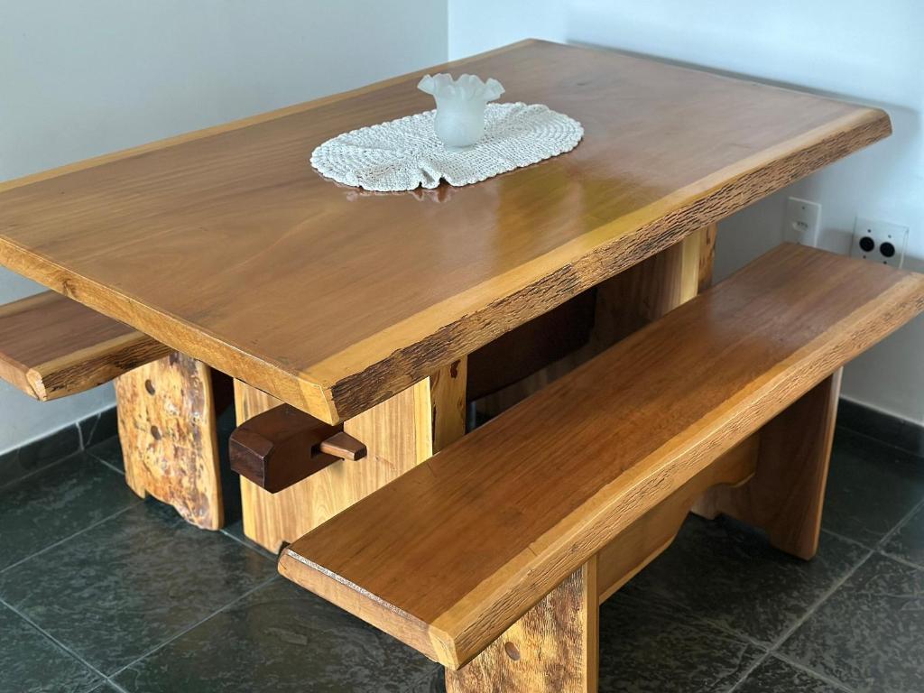 una mesa de madera con dos bancos de madera y una mesa en A 3 min do Mar e 5 da Feirinha - Guilhermina!, en Praia Grande