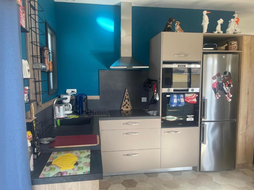 a kitchen with a blue wall and a refrigerator at T3 Cros De Cagnes Bord De plage in Cagnes-sur-Mer
