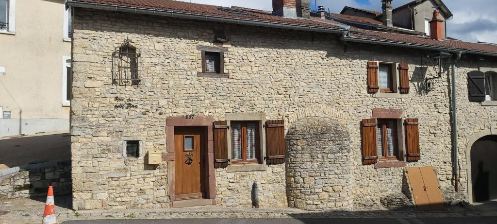 an old stone building with wooden doors and windows at Petite maison en pierre in Vittel