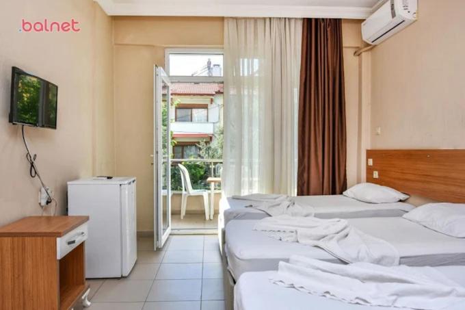 a hotel room with three beds and a balcony at Özden Pansiyon in Burhaniye