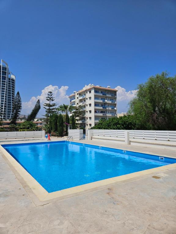 a blue swimming pool with a building in the background at Beachfront Amazing New Apartment in Limassol