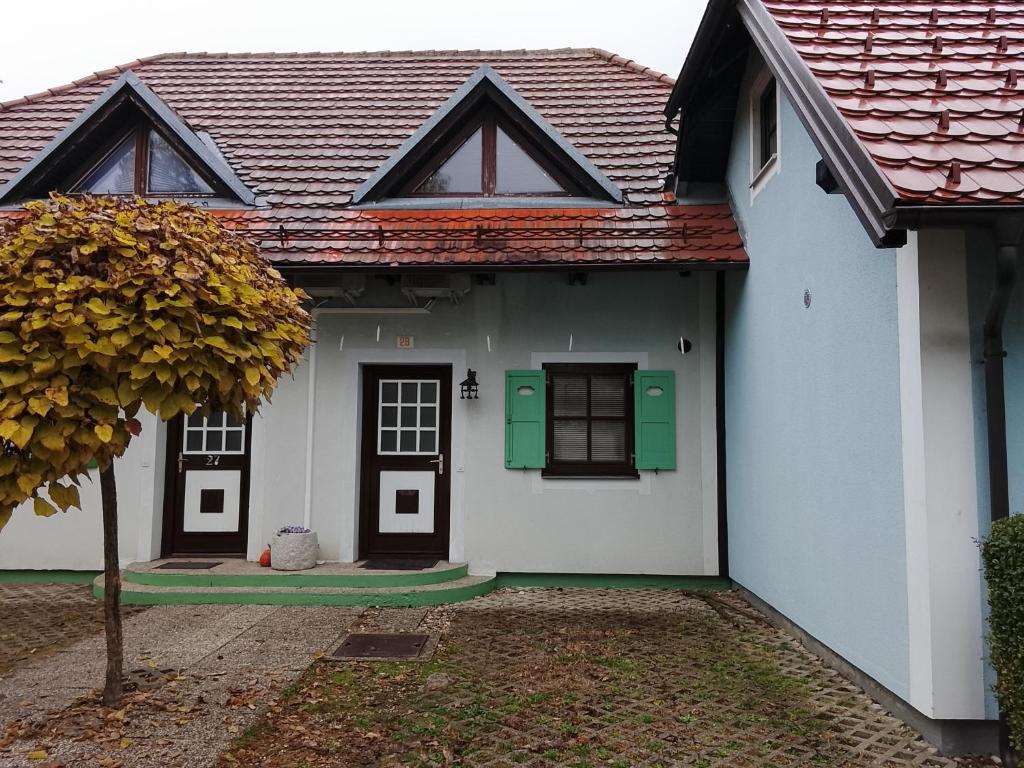 a white house with green doors and a tree at Melisa's Holiday Home in Mostec