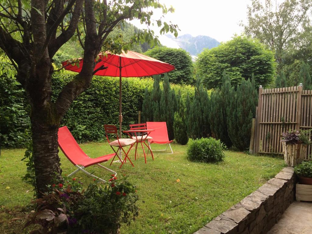 two chairs and a table with an umbrella in a yard at chalet des petits loups in Chamonix-Mont-Blanc