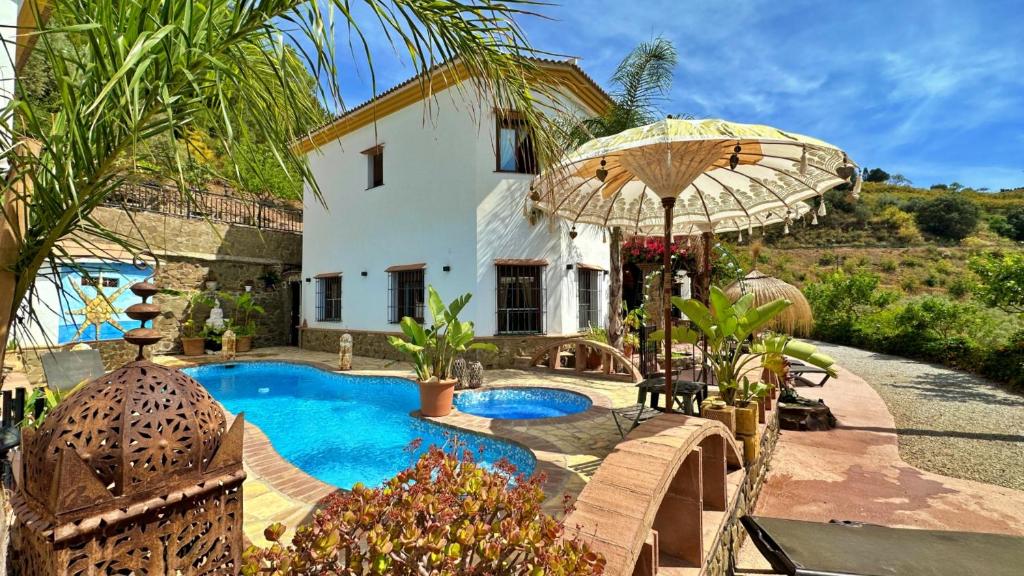 a house with a swimming pool and an umbrella at Villa Malaga con Jacuzzi Piscina vallada Barbacoa By AndaraHolidays in Sayalonga