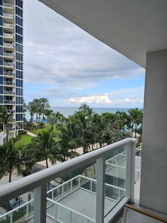 a balcony with a view of the ocean and palm trees at Sunny Isles Oceanfront Apartment for Two in Sunny Isles Beach