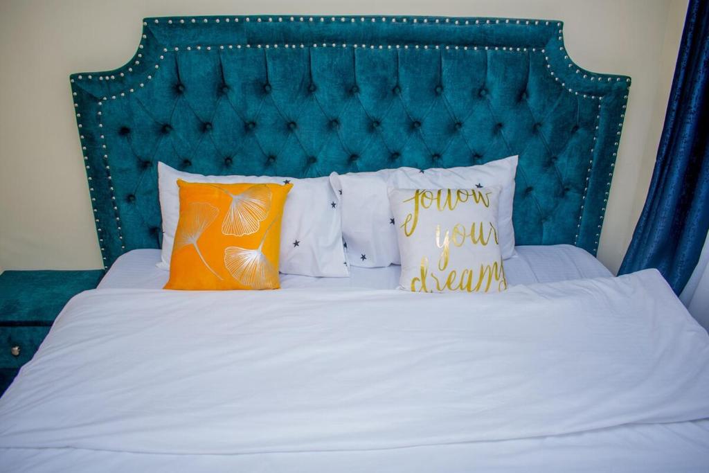 ein Bett mit einem grünen Kopfteil und Kissen darauf in der Unterkunft Danross Nest in Gatunga