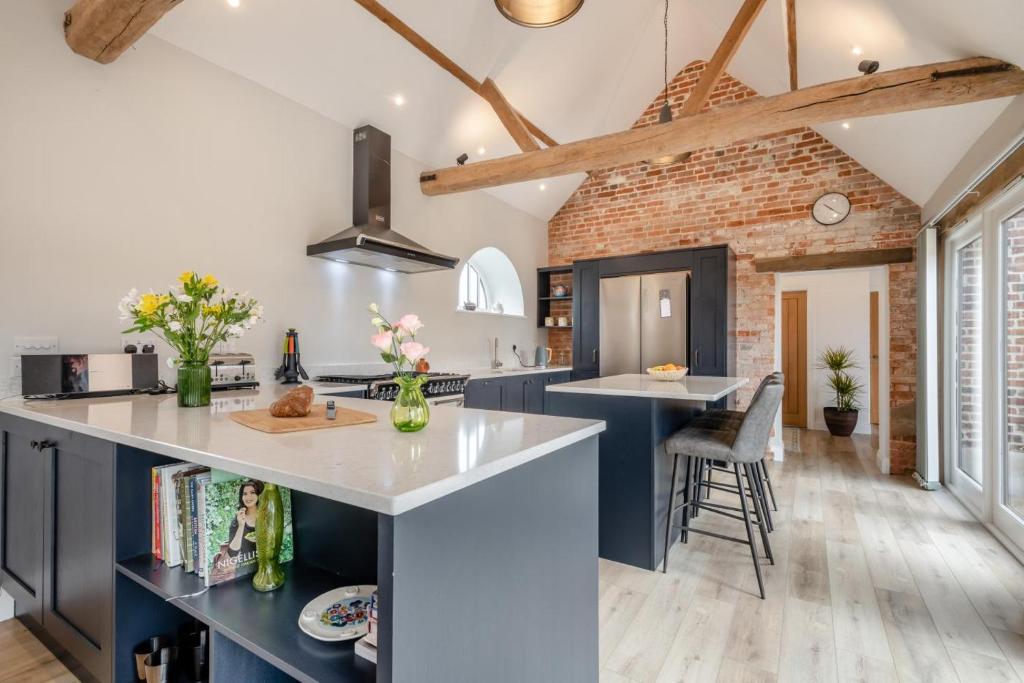 une cuisine avec des placards bleus et un mur en briques dans l'établissement Iken Barn, à Neatishead