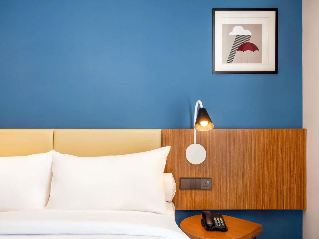 Un dormitorio con una cama con una pared azul. en ibis Styles Bogor Pajajaran, en Bogor