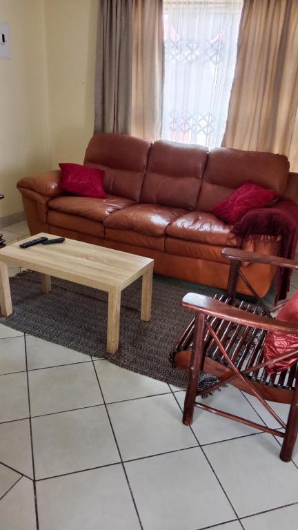 a living room with a brown couch and a coffee table at NEMARA Self Catering Lodge in Polokwane