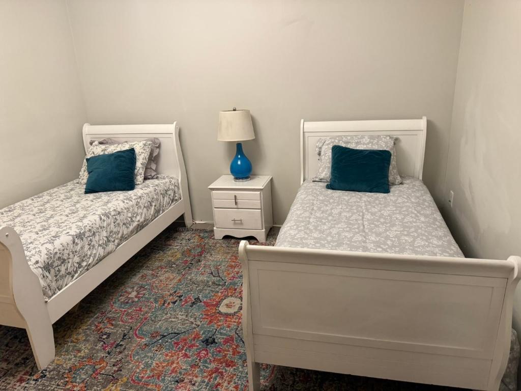 a bedroom with two beds and a lamp on a carpet at designer abode condo min to Manhattan in jersey city in Jersey City