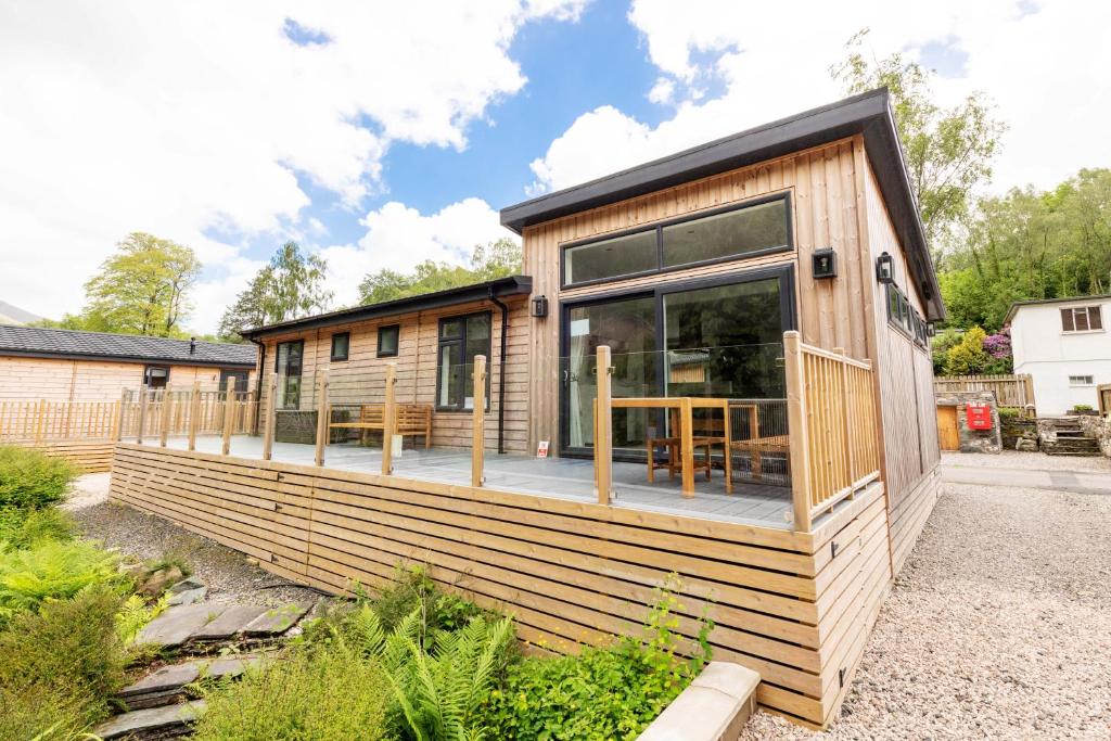 een klein huisje met een groot raam op het dek bij Great Gable Riverside Luxury Lodge in Keswick