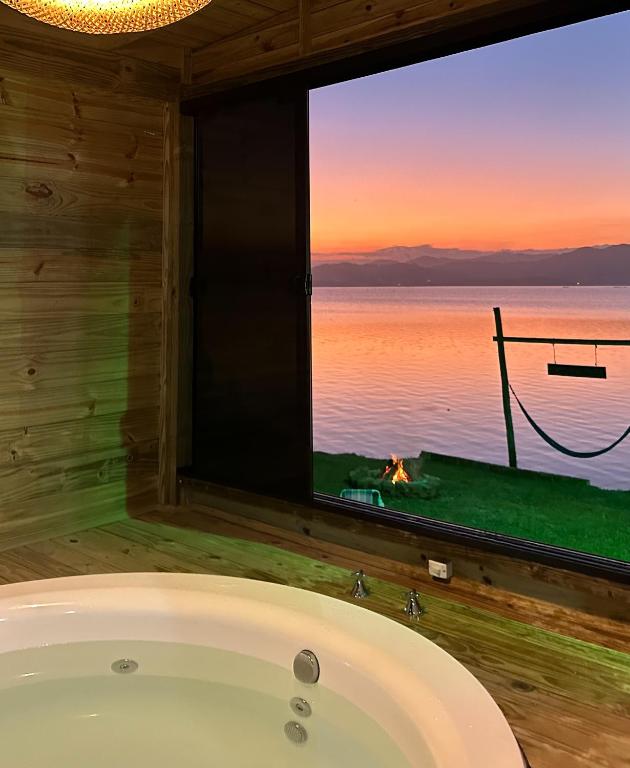a bath tub in a room with a view of the ocean at Chalé na beira da lagoa com vista in Imbituba