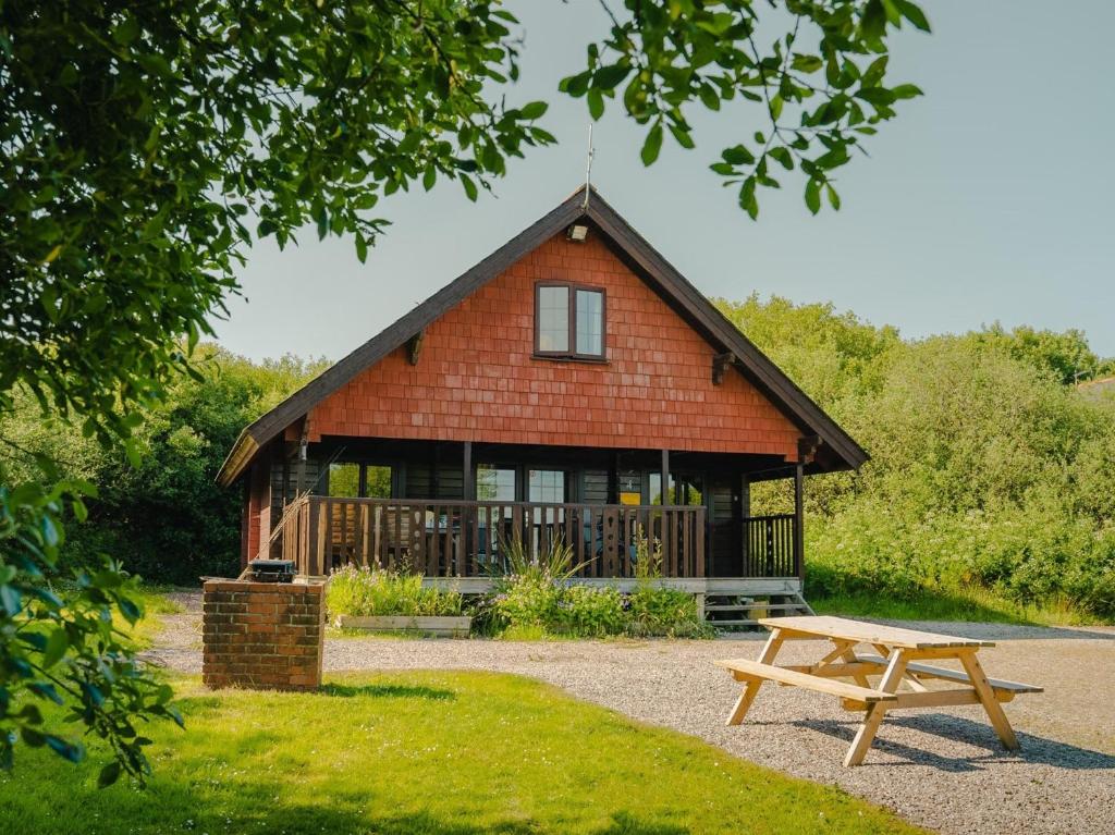 a wooden house with a picnic table and a bench at 3 Bed in Clovelly 00369 in Clovelly