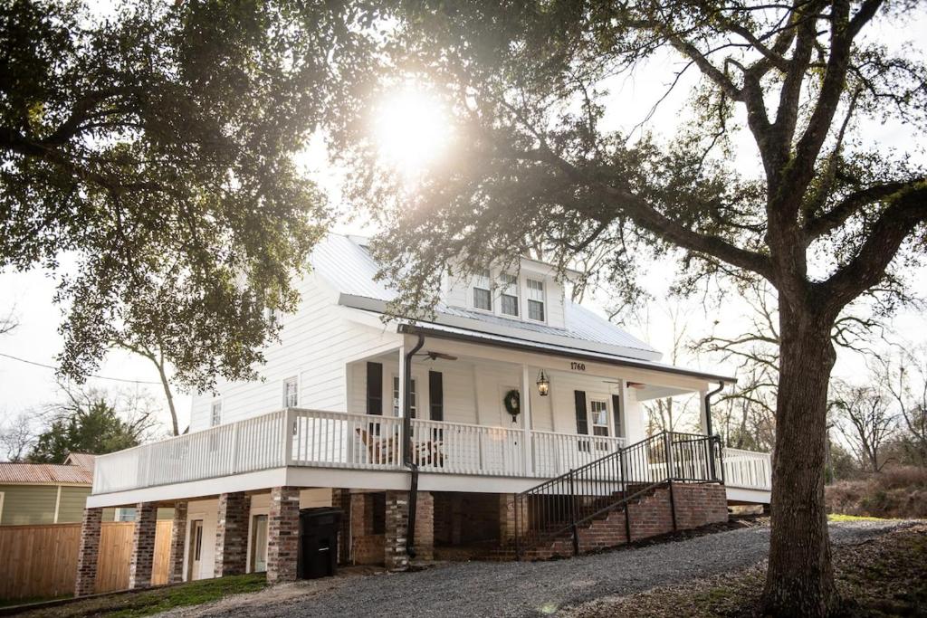 a white house with a porch and a tree at Little Noone in Jackson
