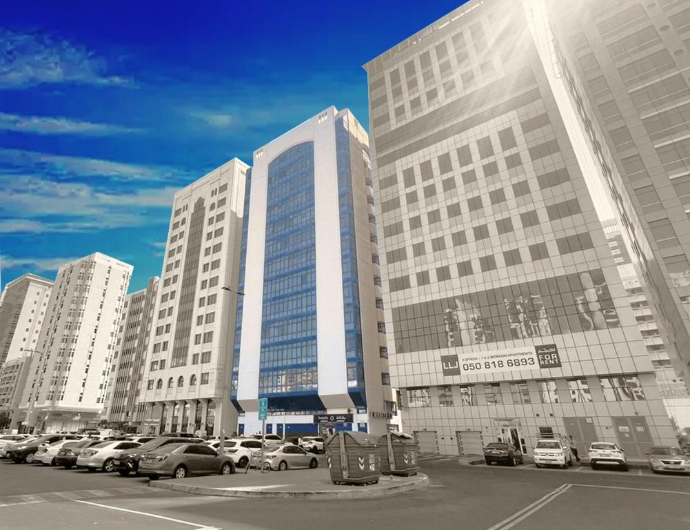 a large building with cars parked in a parking lot at XD Hostel Apartments in Abu Dhabi