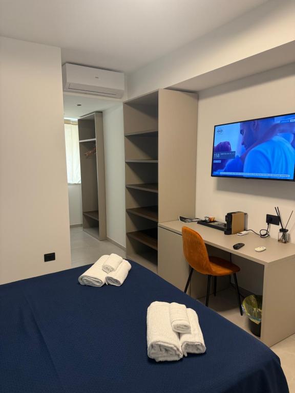 ein Zimmer mit einem Bett, einem Schreibtisch und einem Fernseher in der Unterkunft Sunset Affittacamere in Cipollina