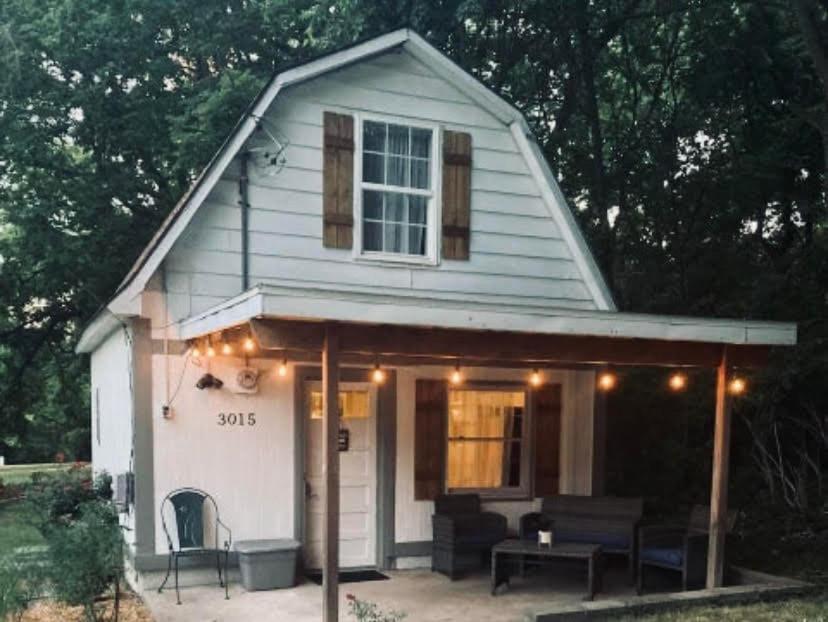 ein kleines weißes Haus mit einer Veranda mit Lichtern darauf in der Unterkunft Galloway Cottage- Bikes & Firepit in Springfield