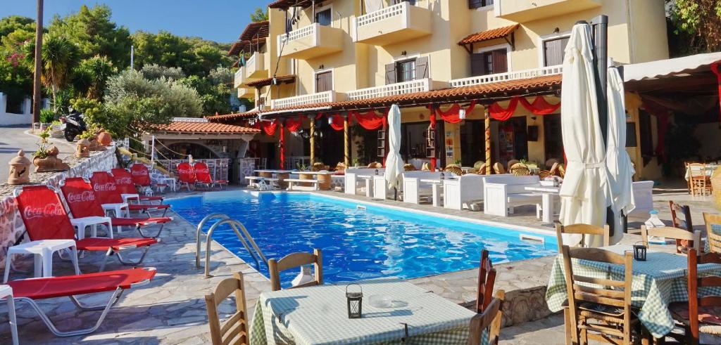 a swimming pool with tables and chairs next to a building at Vasilaras Hotel in Skala