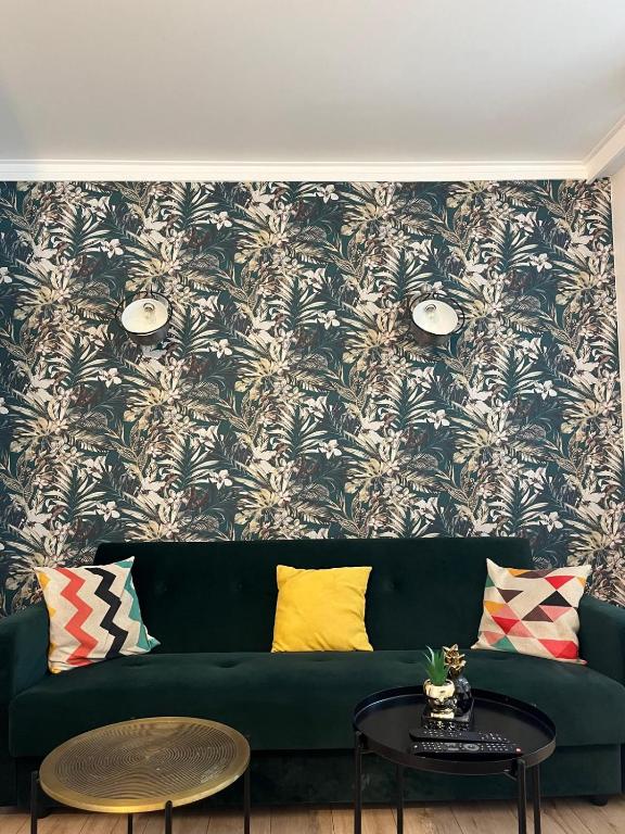 a green couch in a living room with a floral wallpaper at Beautiful flat in Issy les Moulineaux - Close to Paris in Issy-les-Moulineaux
