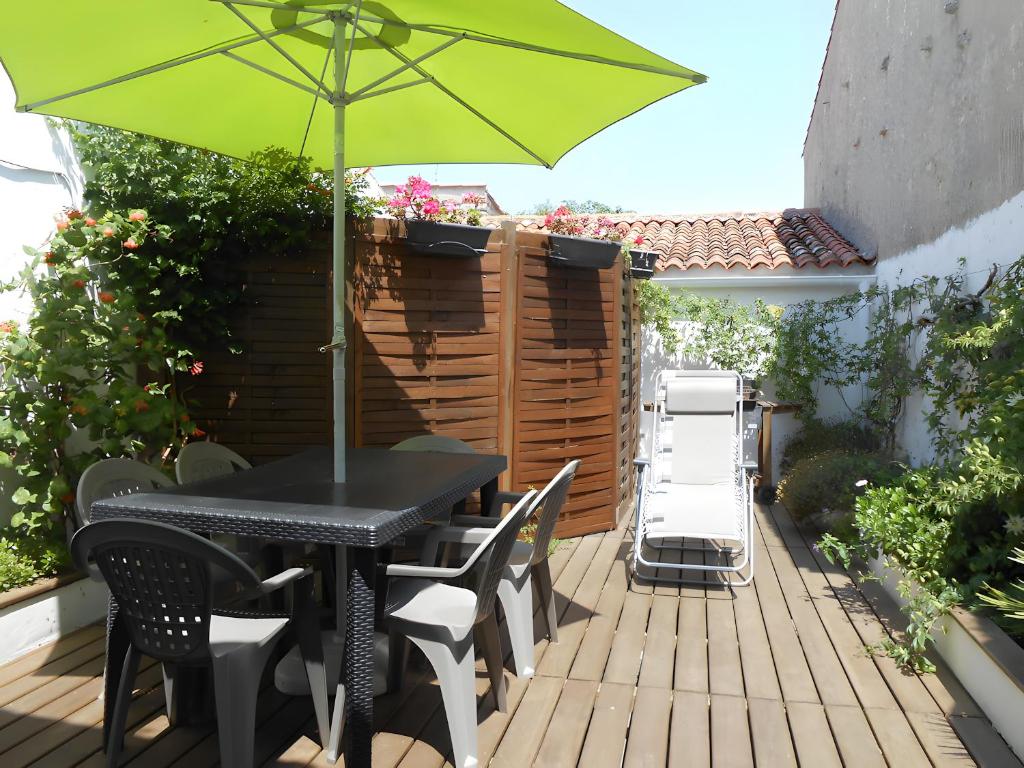 a table and chairs with a green umbrella on a deck at Villa des Ormeaux in Les Moulins de la Boire