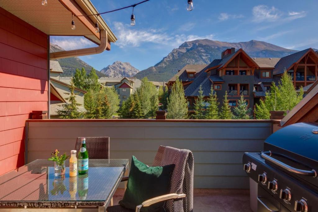 a patio with a table and a grill and mountains at Lovely 2BR Canmore Condo w Heated Pool and Hot Tub in Canmore