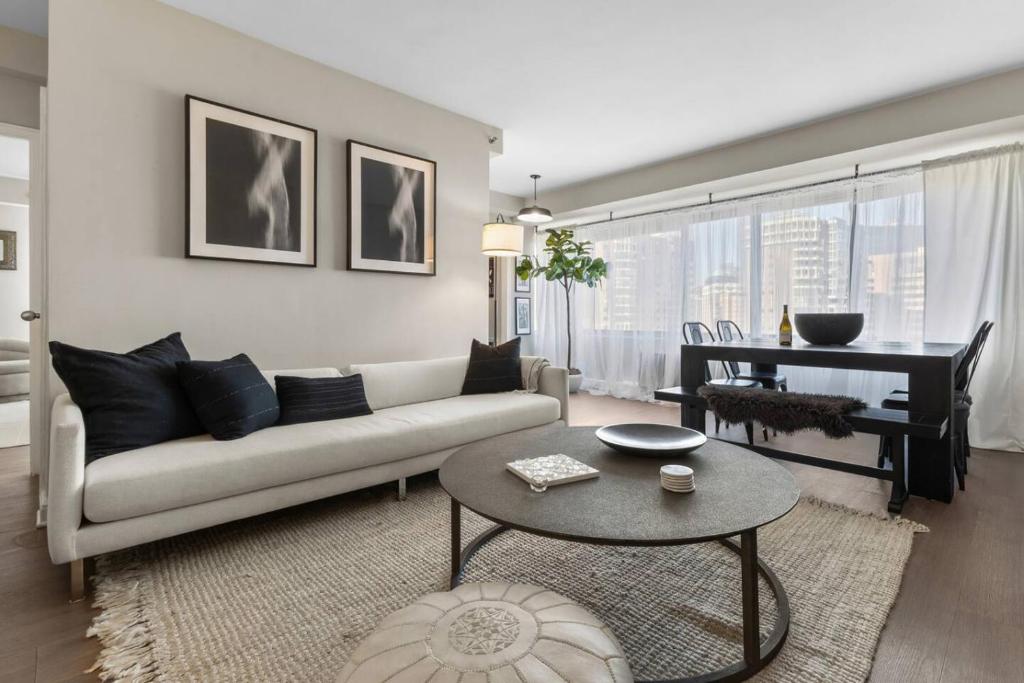 een woonkamer met een bank, een tafel en een piano bij Elevated Minimalist Escape - Free Parking and Metro - The Sutton in Radnor Heights