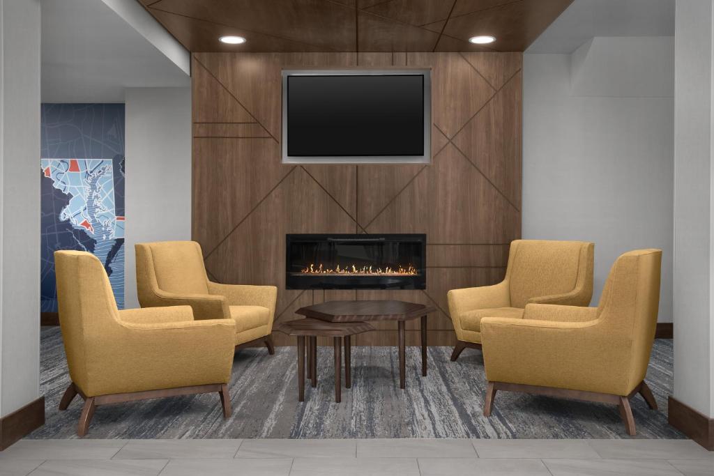 vestíbulo con chimenea, sillas y TV en Holiday Inn Express Baltimore - BWI Airport NE by IHG, en Baltimore