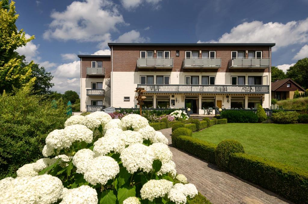 een groot gebouw met witte bloemen ervoor bij Hotel Bemelmans in Schin op Geul