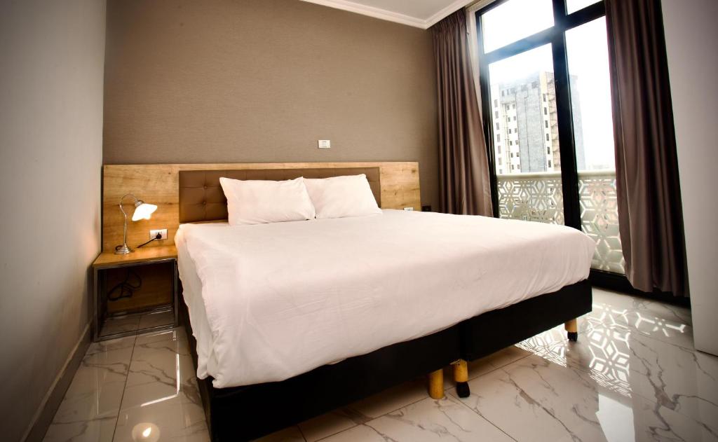 a bedroom with a large bed and a window at Le Basilic Hotel Apartment & Spa in Addis Ababa