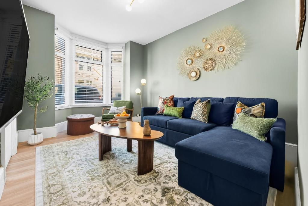 ein Wohnzimmer mit einem blauen Sofa und einem Tisch in der Unterkunft 3-Bedroom Stunning, Cosy, Luxurious House in Fratton, Sleeps 8 with Parking, Pet-Friendly - LONG TERM STAY SPECIAL OFFER AVAILABLE! - by Blue Puffin Stays in Portsmouth