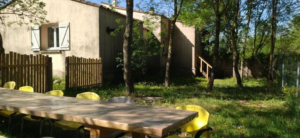 a wooden table and yellow chairs in a yard at Le Mas Mouth in Montoulieu