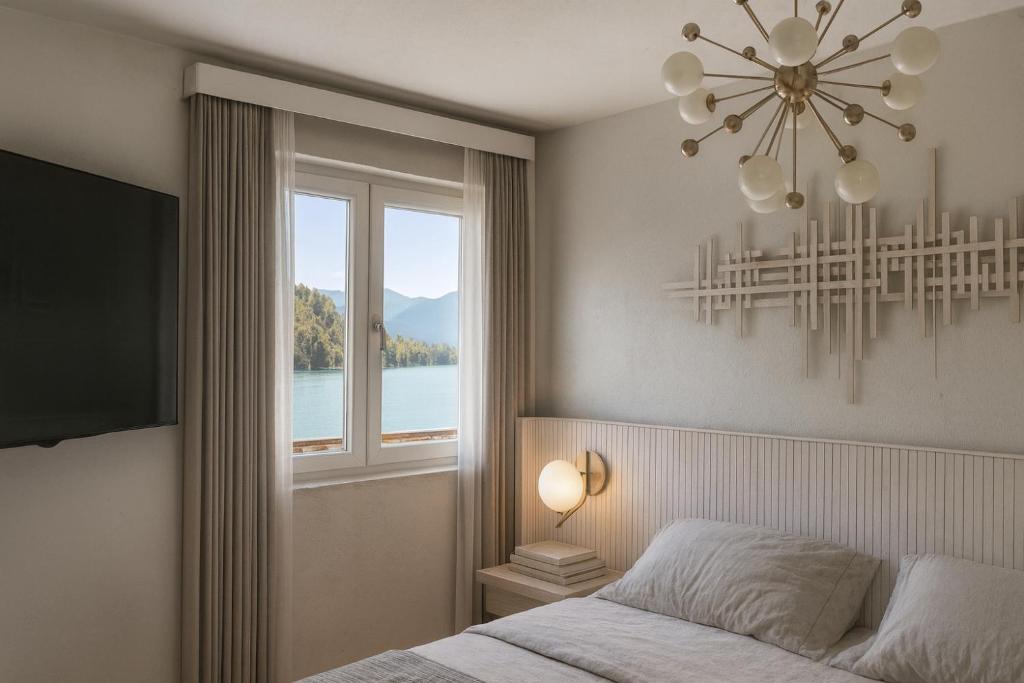 a bedroom with a chandelier and a bed and a window at Lake Lodge Ossiacher See in Annenheim