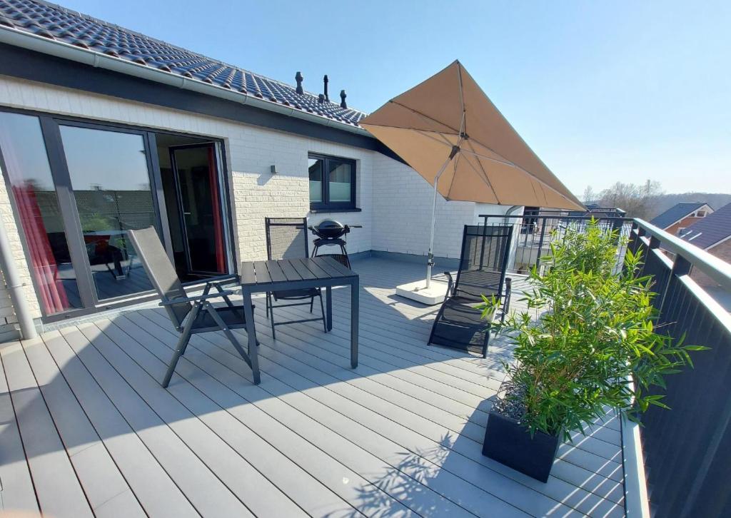 a deck with a table and an umbrella at Neue Liebe Haffkrug 5 - Meeresstern in Haffkrug