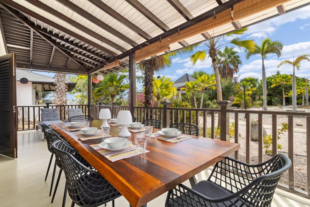 einen Holztisch und Stühle auf einer Terrasse mit einem Zaun in der Unterkunft 3bdr, with tropical garden & pool in Kralendijk! in Kralendijk