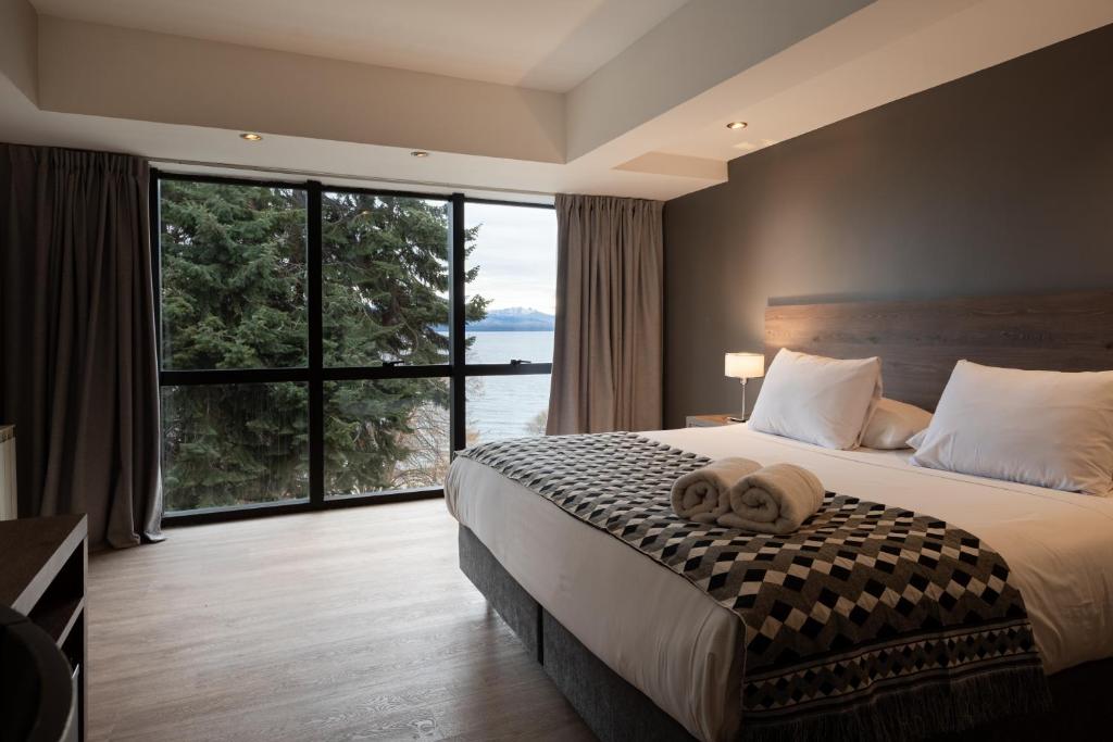 a bedroom with a large bed with two towels on it at Hotel Alt Interlaken in San Carlos de Bariloche