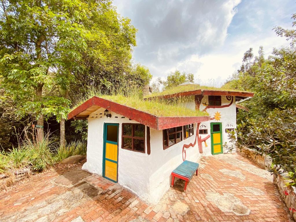 a small house with a grass roof and a bench at Jardin Colibri RNT 33633 in Guatavita