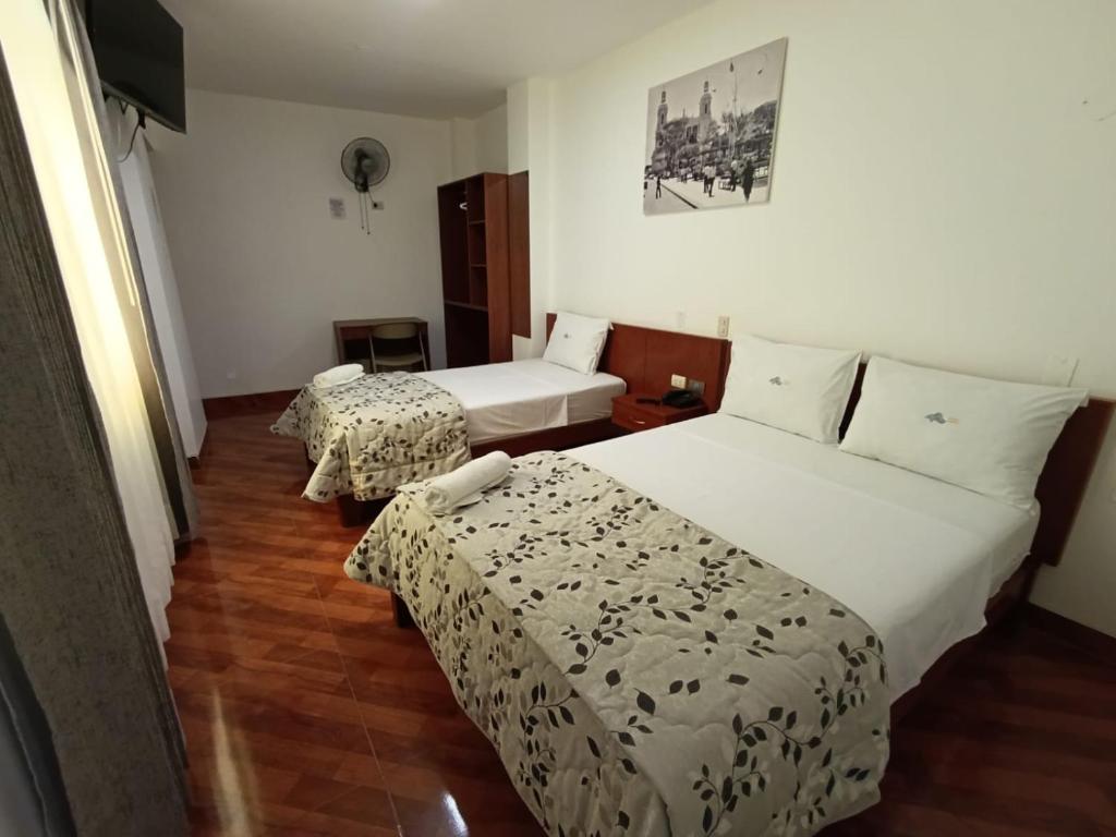 a hotel room with two beds and two tables at Misky Puñuy in Chiclayo